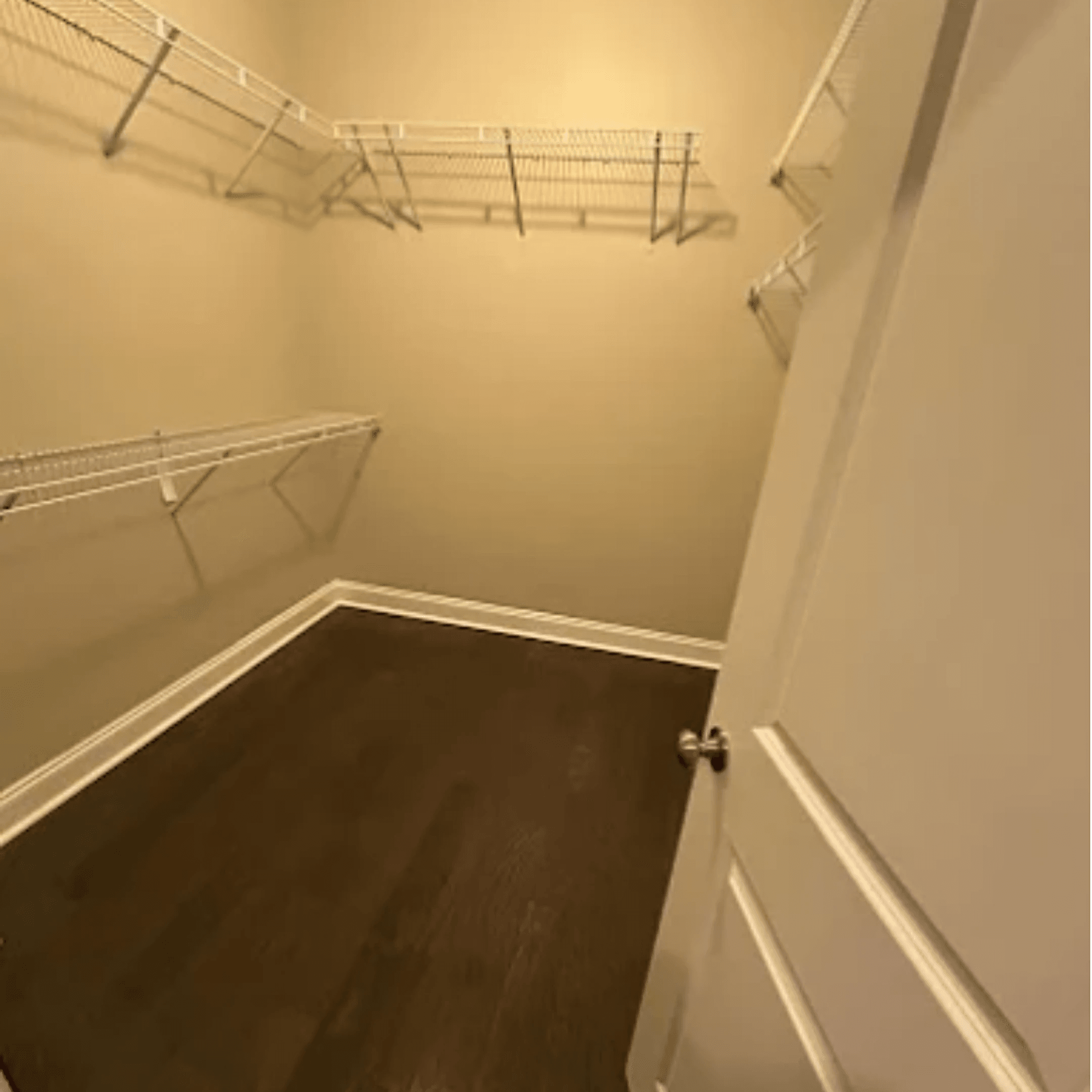 Empty walk-in closet with bare shelves and clean floors, ready to hand back the keys