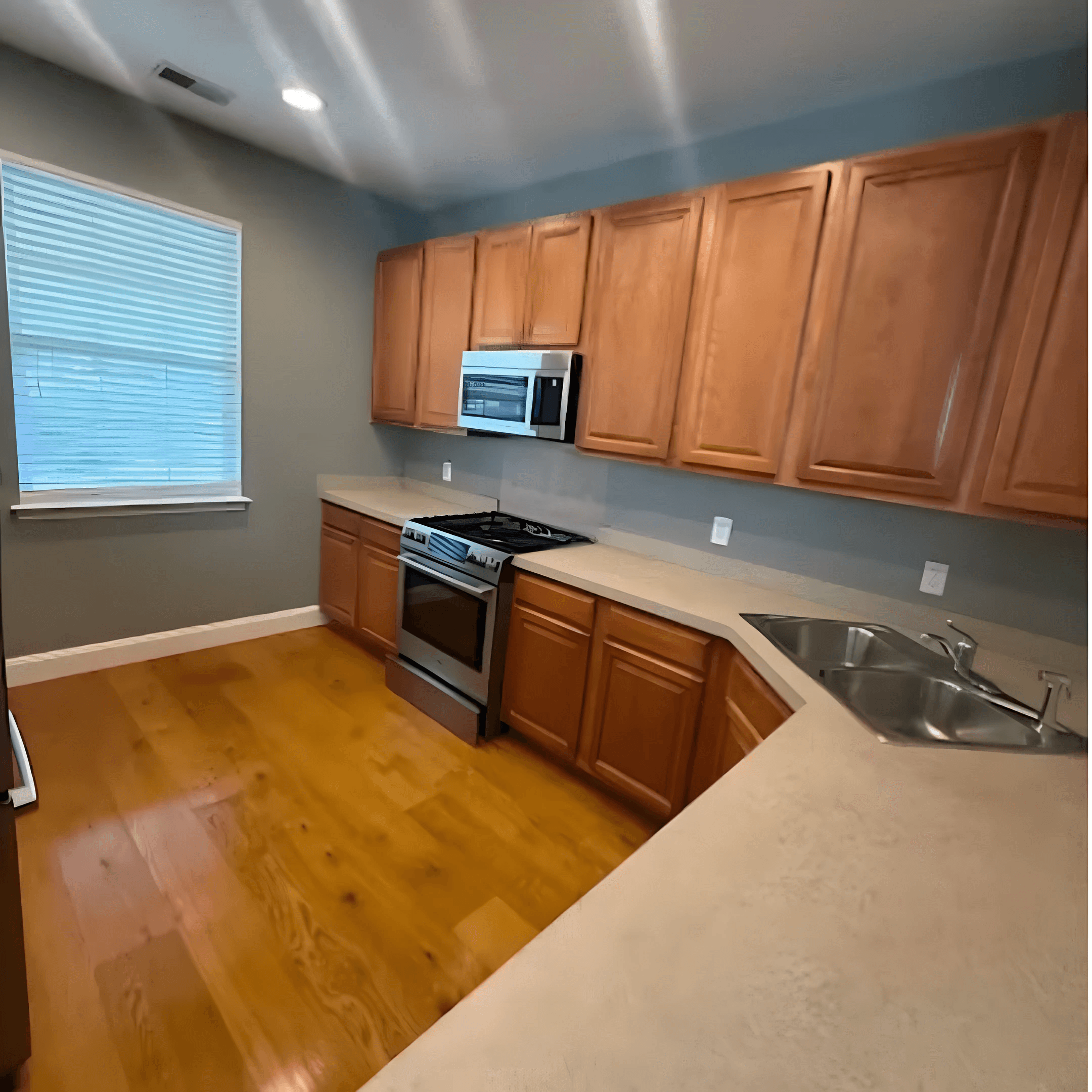 Empty kitchen with wood cabinets and wiped-down counters, ready for move-in